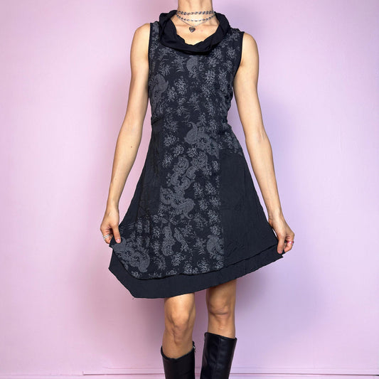 The Y2K Black Asymmetric Mini Dress is a vintage 2000s dress featuring an elegant paisley print and a deconstructed layered design. The cowl neckline and sleeveless cut create a soft, fluid silhouette, while the asymmetric hem adds a playful edge. Made with slightly crinkled fabric, it offers a flattering A-line shape. Perfect for artsy, indie, or witchy Y2K-inspired looks. Great vintage condition.