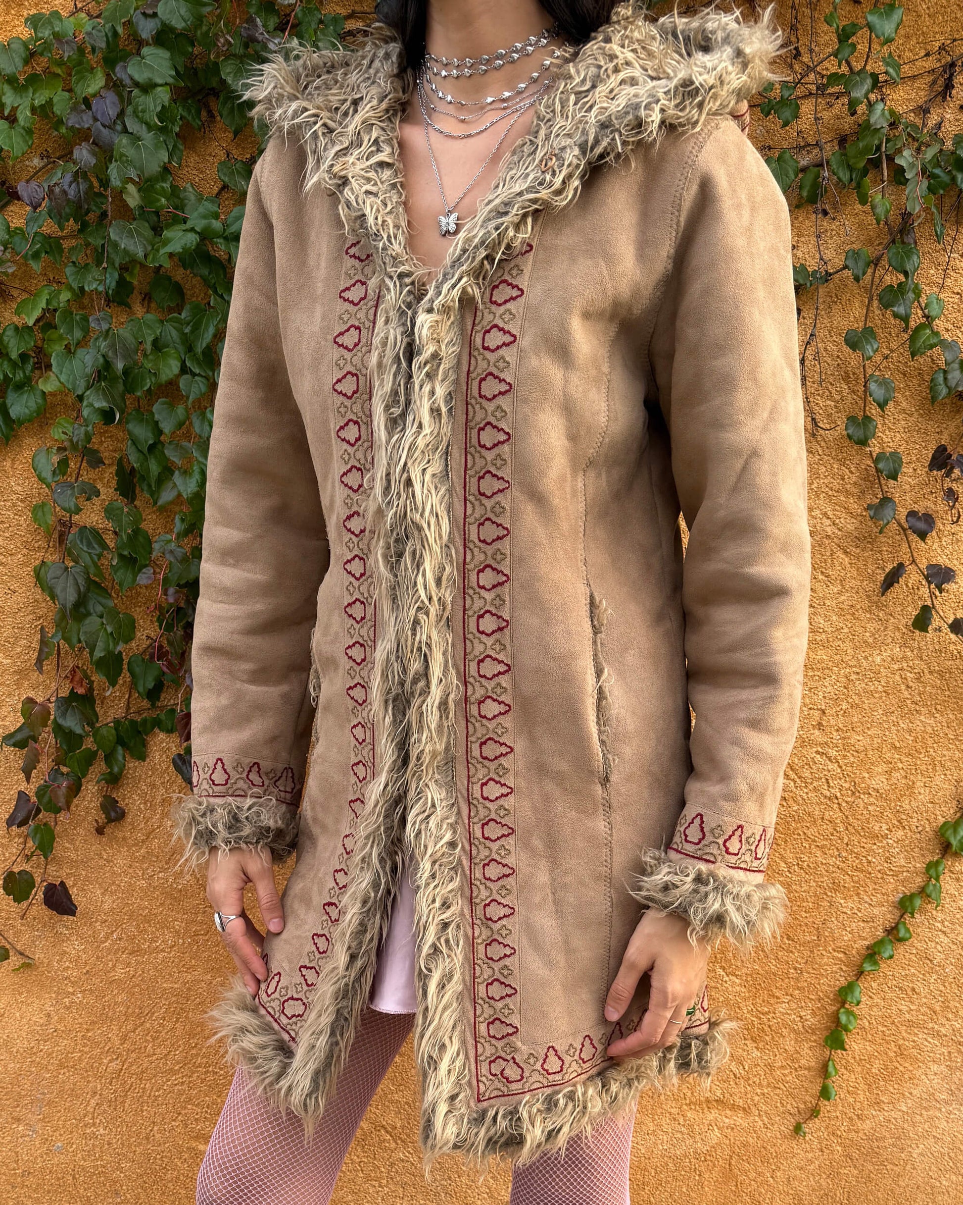 Vintage 2000s beige Penny Lane coat with a 70s boho hippie influence, featuring a hood, faux fur lining and faux fur cuffs. Designed with hook closures, front pockets, and red and brown embroidered details that give it a charming Afghan-inspired look. Warm, cozy, and super cute for winter styling, perfect as an iconic Y2K cold-weather essential. Great vintage condition.