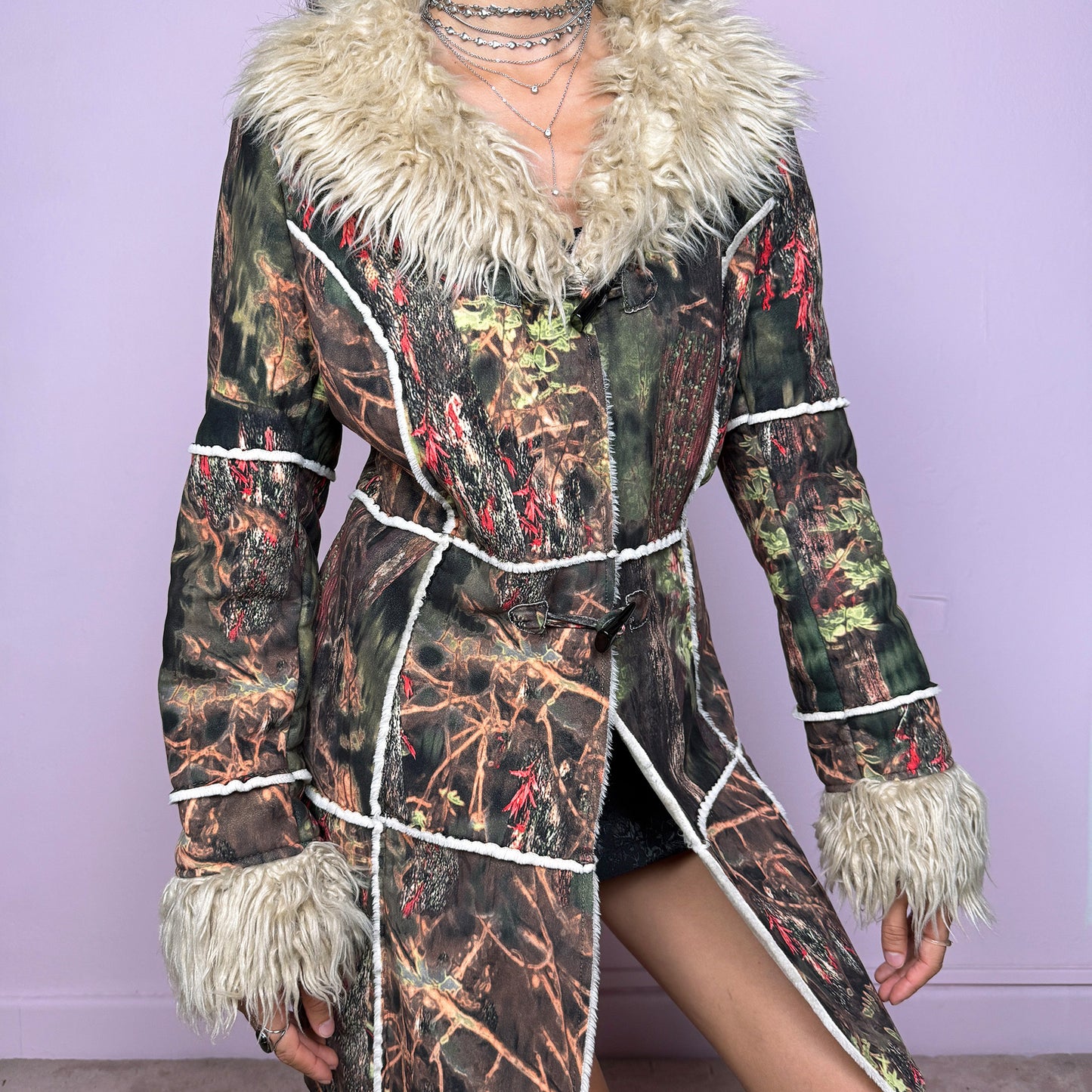 This vintage 2000s Penny Lane coat features a surreal forest graphic print in earthy greens, browns, and red tones, trimmed with plush beige faux fur at the collar and cuffs. Designed with toggle closures, contrast seams and pockets, it evokes fairycore and woodland Y2K energy with bohemian allure. Cozy yet bold, perfect for winter layering and statement street styling. A collectible archive outerwear piece. Made from warm polyester blend. Excellent vintage condition.