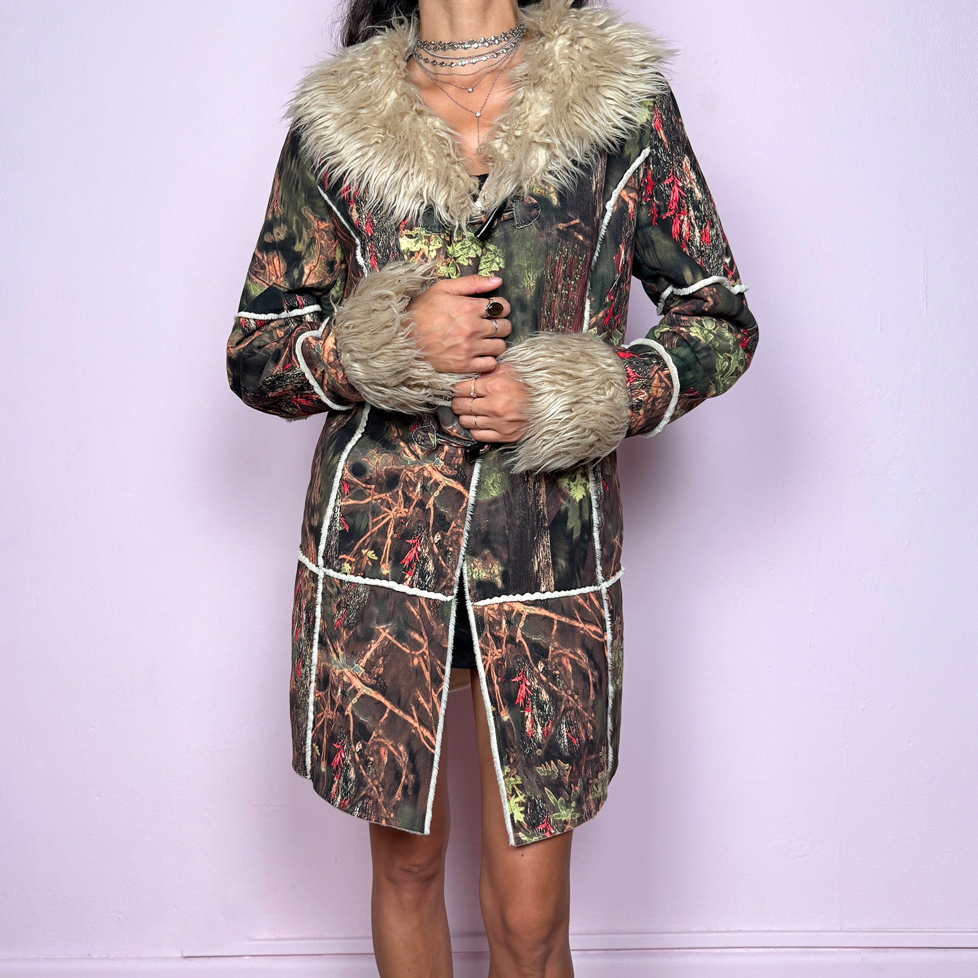 This vintage 2000s Penny Lane coat features a surreal forest graphic print in earthy greens, browns, and red tones, trimmed with plush beige faux fur at the collar and cuffs. Designed with toggle closures, contrast seams and pockets, it evokes fairycore and woodland Y2K energy with bohemian allure. Cozy yet bold, perfect for winter layering and statement street styling. A collectible archive outerwear piece. Made from warm polyester blend. Excellent vintage condition.